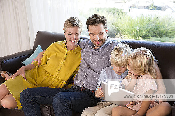 Familie sitzt zu Hause auf der Couch mit Tablette