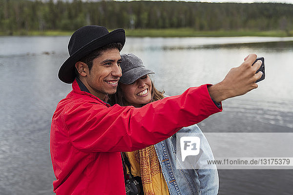 Finland  Lapland  happy couple taking a selfie at a lake