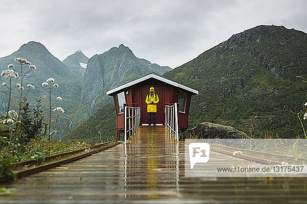 Mann in gelber Regenjacke wartet in roter Holzhütte  Lappland  Norwegen