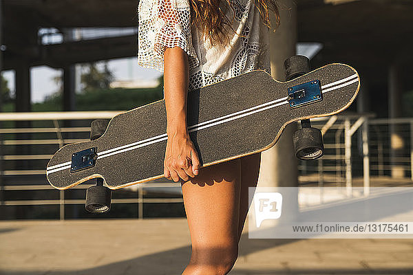 Close-up of woman holding skateboard in the city