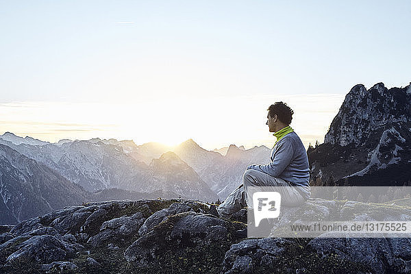 Österreich  Tirol  Rofangebirge  Wanderer bei Sonnenuntergang auf Felsen sitzend