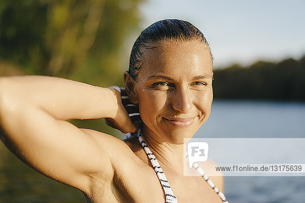 Porträt einer lächelnden Frau mit nassem Haar an einem See