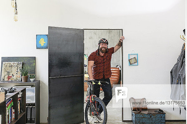 Portrait of laughing man with bicycle in office