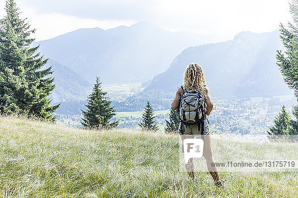 Deutschland  Bayern  Oberammergau  junge Frau wandert stehend auf der Bergwiese