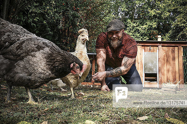 Mann im eigenen Garten  Mann beim Füttern von Freilandhühnern