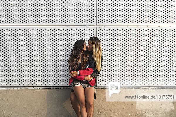 Lesbisches Paar umarmt sich an einer Wand
