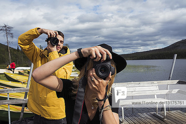 Finnland  Lappland  Mann und Frau beim Fotografieren auf einem Steg an einem See