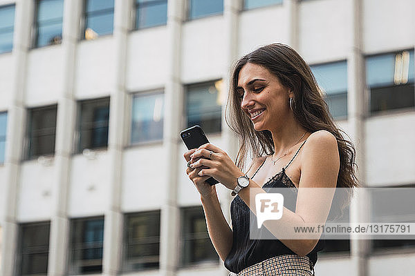 Lächelnde junge Frau benutzt Mobiltelefon