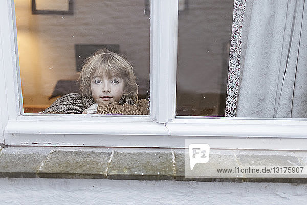 Porträt eines nachdenklichen Jungen  der aus dem Fenster schaut