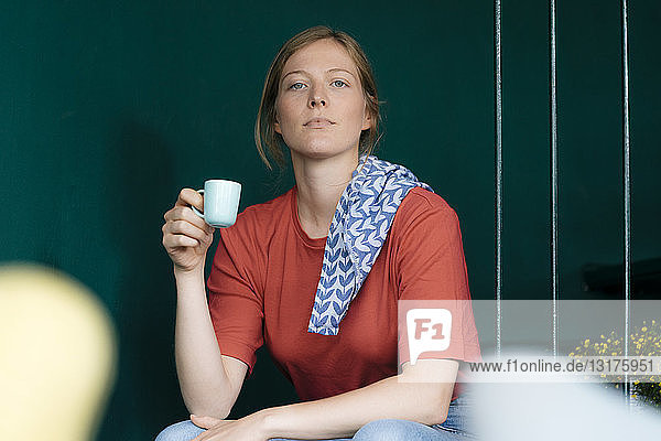 Junge Frau sitzt in einem Café und hält eine Espressotasse