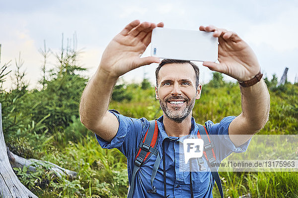 Man taking a selfie with his cell phone during hiking trip