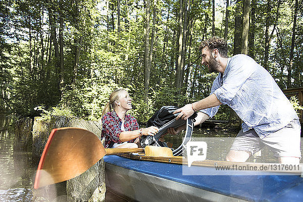 Glückliches junges Paar beim Einsteigen ins Kanu in einem Waldbach