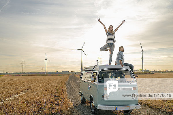 Junges Paar auf dem Dach eines Wohnmobils in ländlicher Landschaft