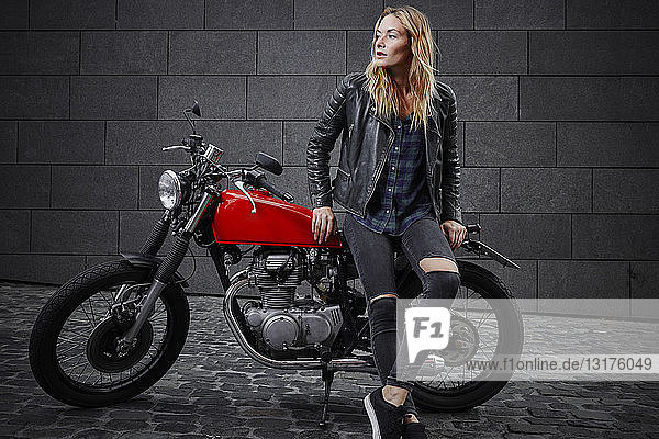 Selbstbewusste junge Frau mit Motorrad schaut weg