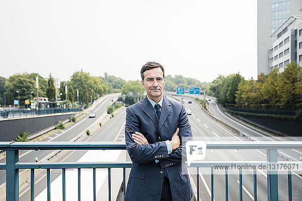Porträt eines selbstbewussten Geschäftsmannes  der auf der Autobahnbrücke steht