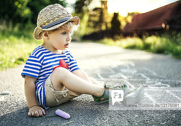 Tagträumendes Kleinkind Junge sitzt auf der Straße