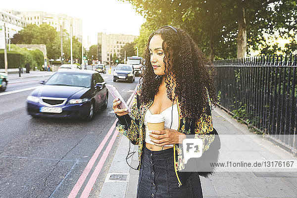 Großbritannien  London  junge Frau mit Handy auf dem Bürgersteig in der Stadt