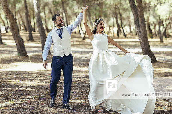 Happy bridal couple dancing together in pine forest