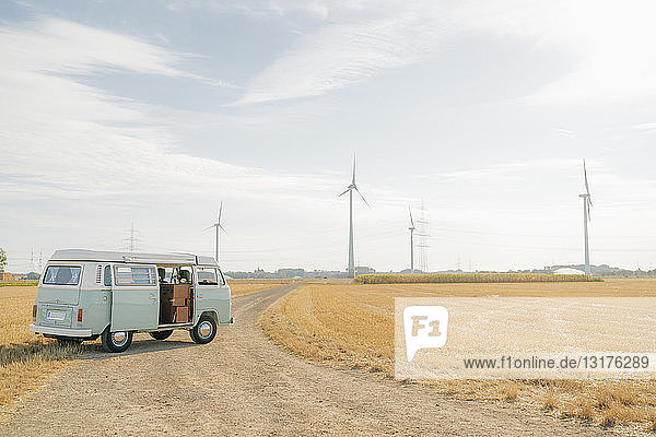 Wohnmobil auf Feldweg in ländlicher Landschaft mit Windturbinen geparkt