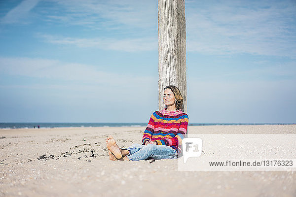 Reife Frau  die sich am Strand entspannt und sich auf eine Stange stützt