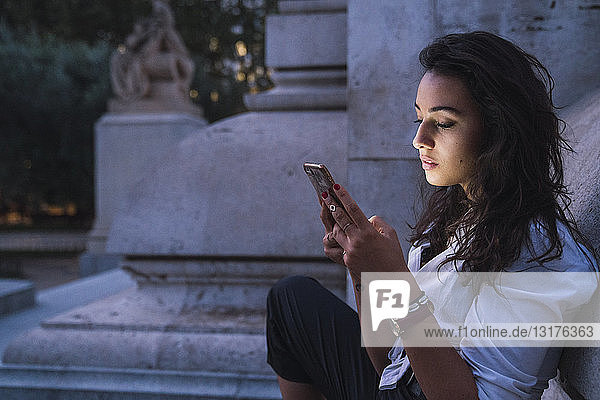 Young woman using cell phone at evening twilight