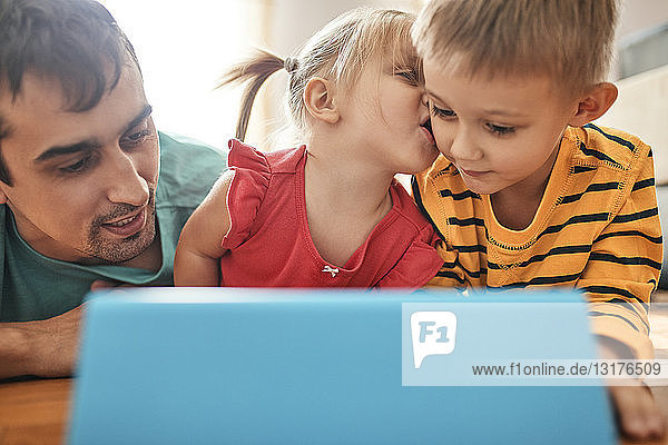 Vater und seine Kinder benutzen digitales Tablett zu Hause