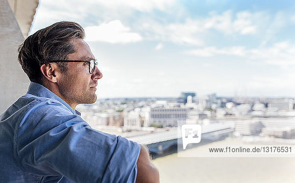 UK  London  Mann betrachtet die Stadt auf einer Dachterrasse