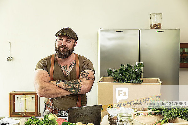 Besitzer eines Lieferdienstes für Bio-Gemüse  der stolz in seiner Küche steht