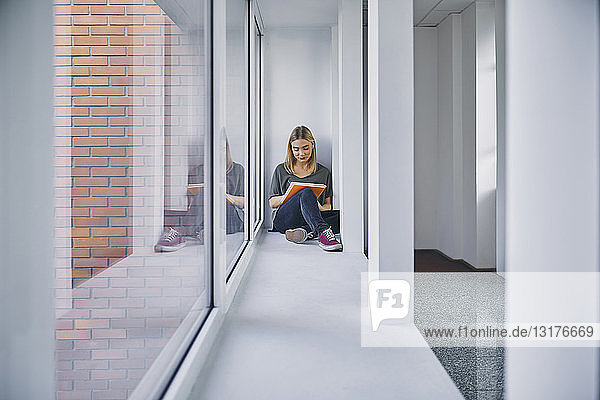 Student sitting at the window in hallway learning