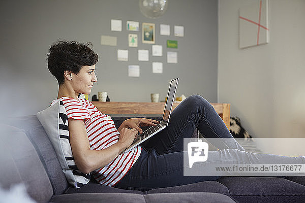 Frau benutzt Laptop auf der Couch zu Hause