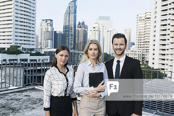 Group of successful business people on city rooftop  holding digital tablet