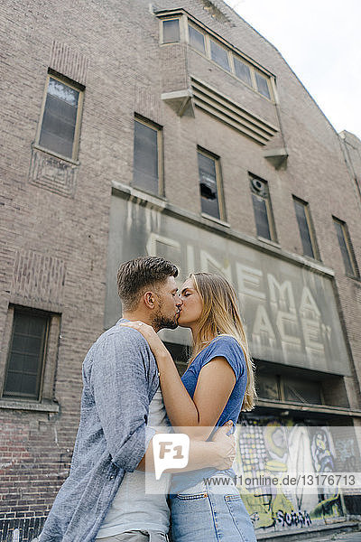 Affectionate young couple kissing in the city in front of a cinema