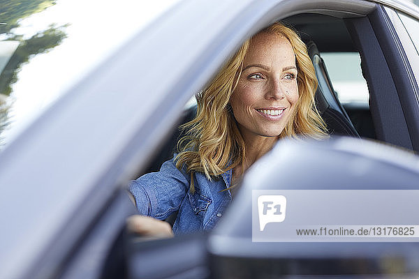 Lächelnde Auto fahrende Frau schaut aus dem Fenster