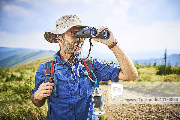 Man looking through binoculars during hiking trip