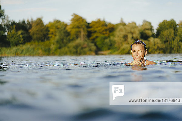 Porträt einer lächelnden Frau  die in einem See schwimmt