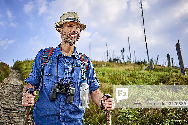 Lächelnder Mann mit Fernglas beim Wandern in den Bergen