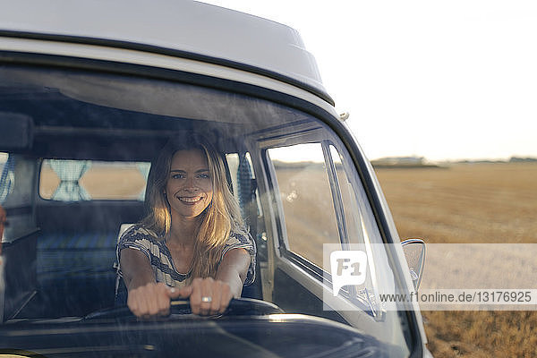 Glückliche junge Frau fährt Wohnmobil in ländlicher Landschaft