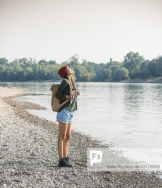 Glückliche junge Frau steht am Flussufer