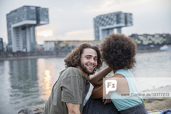 Deutschland  Köln  glückliches Paar entspannt sich bei Sonnenuntergang am Flussufer