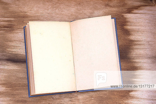 Aufgeschlagenes altes Buch mit leeren Seiten auf Holz