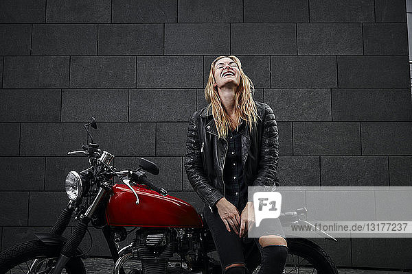 Porträt einer lachenden jungen Frau mit Motorrad