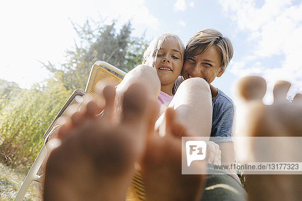Mother and daughter having fun in garden showing their feet