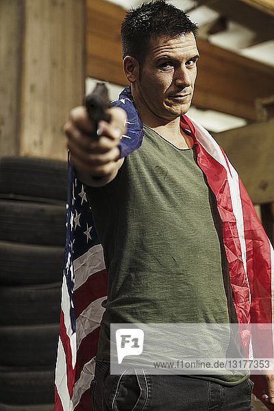 Portrait of man wearing American flag aiming with a gun