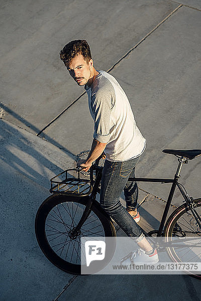 Junger Mann mit Pendler-Fixie-Fahrrad auf Betonplatten
