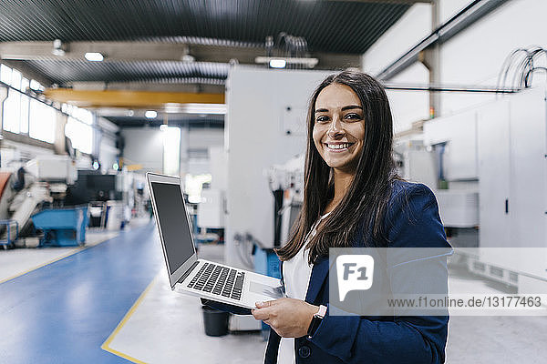 Selbstbewusste Frau  die in einem High-Tech-Unternehmen arbeitet und einen Laptop hält