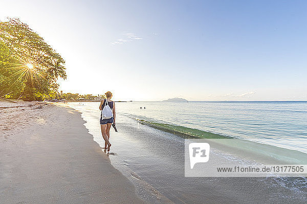 Seychellen  Mahe  Beau Vallon Beach  Frau  die bei Sonnenuntergang am Strand spazieren geht