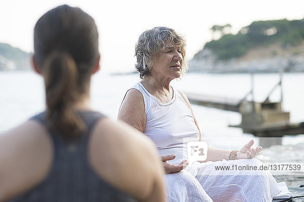 Senior woman doing a yoga exercise at the coast