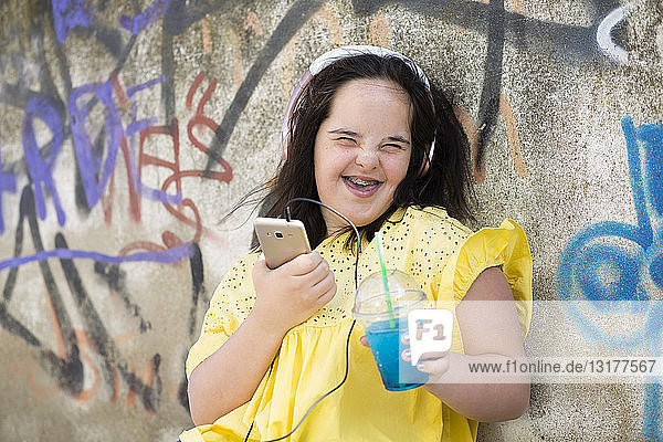Teenager mit Down-Syndrom benutzt Smartphone  hält Plastikbecher