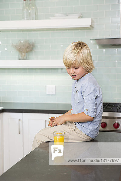 Junge in der Küche mit einem Glas Orangensaft