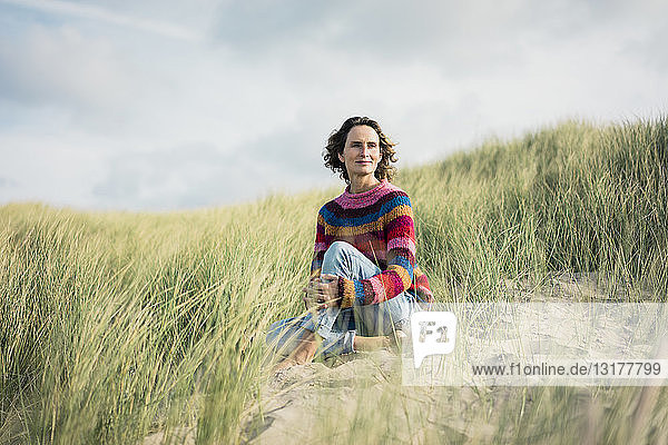 Mature woman relaxing on the beach  sitting in the dunes